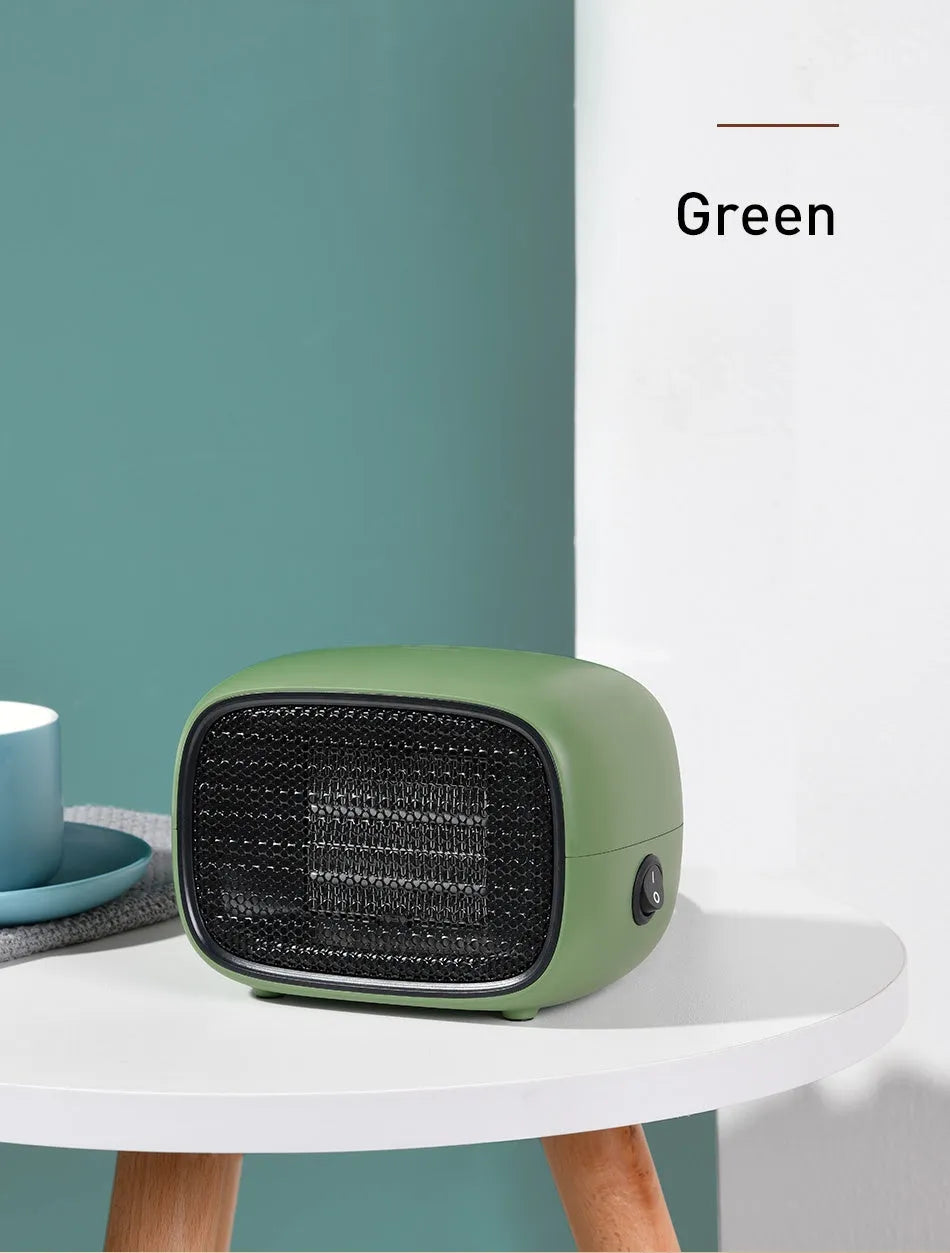 Green mini PTC ceramic heater with metal mesh front on a wooden desk
