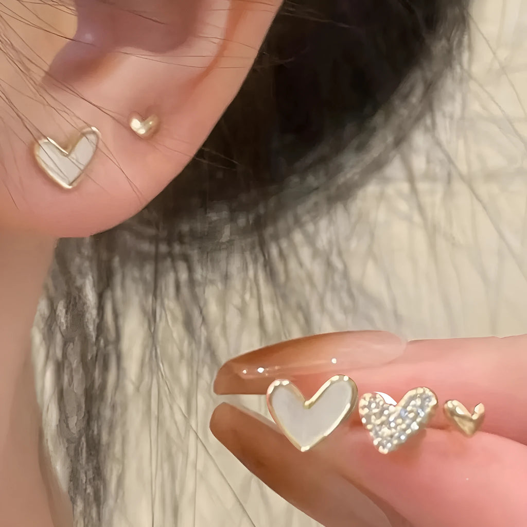 Three pairs of women's heart-shaped alloy earrings in gold, black, white and pink electroplated finishes