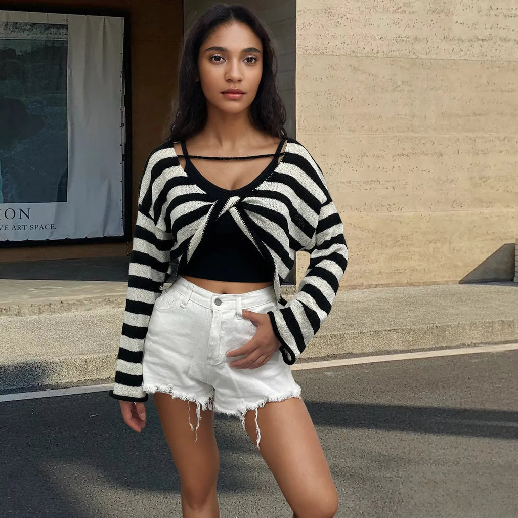 Black and white striped cropped sweater with long sleeves on a woman, showing exposed navel detail.