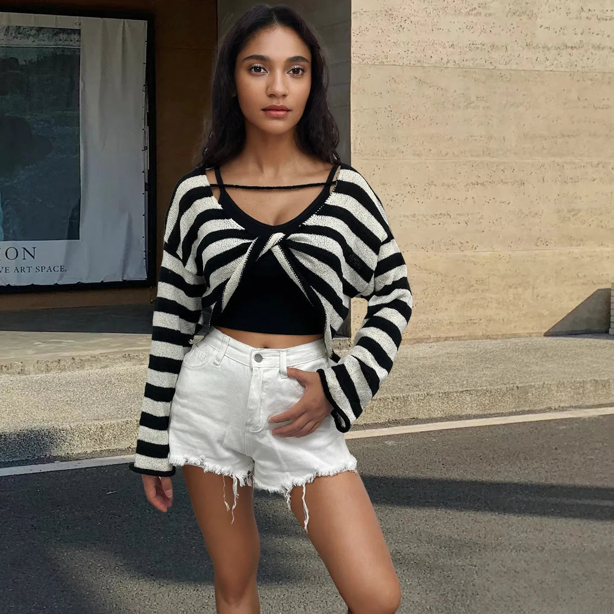 Black and white striped cropped sweater with long sleeves on a woman, showing exposed navel detail.