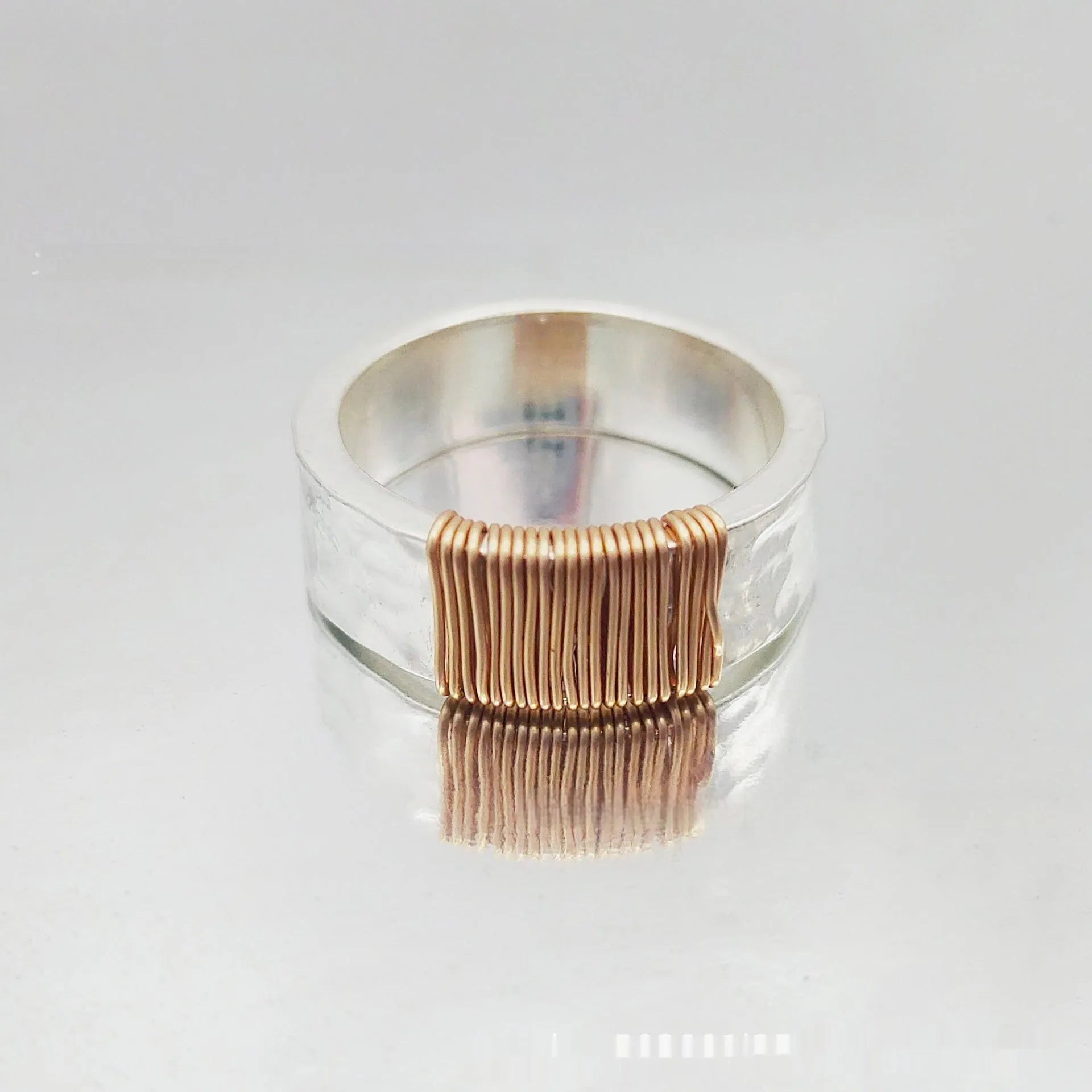Geometric copper bracelet with irregular coil design and silver-gold electroplated finish.
