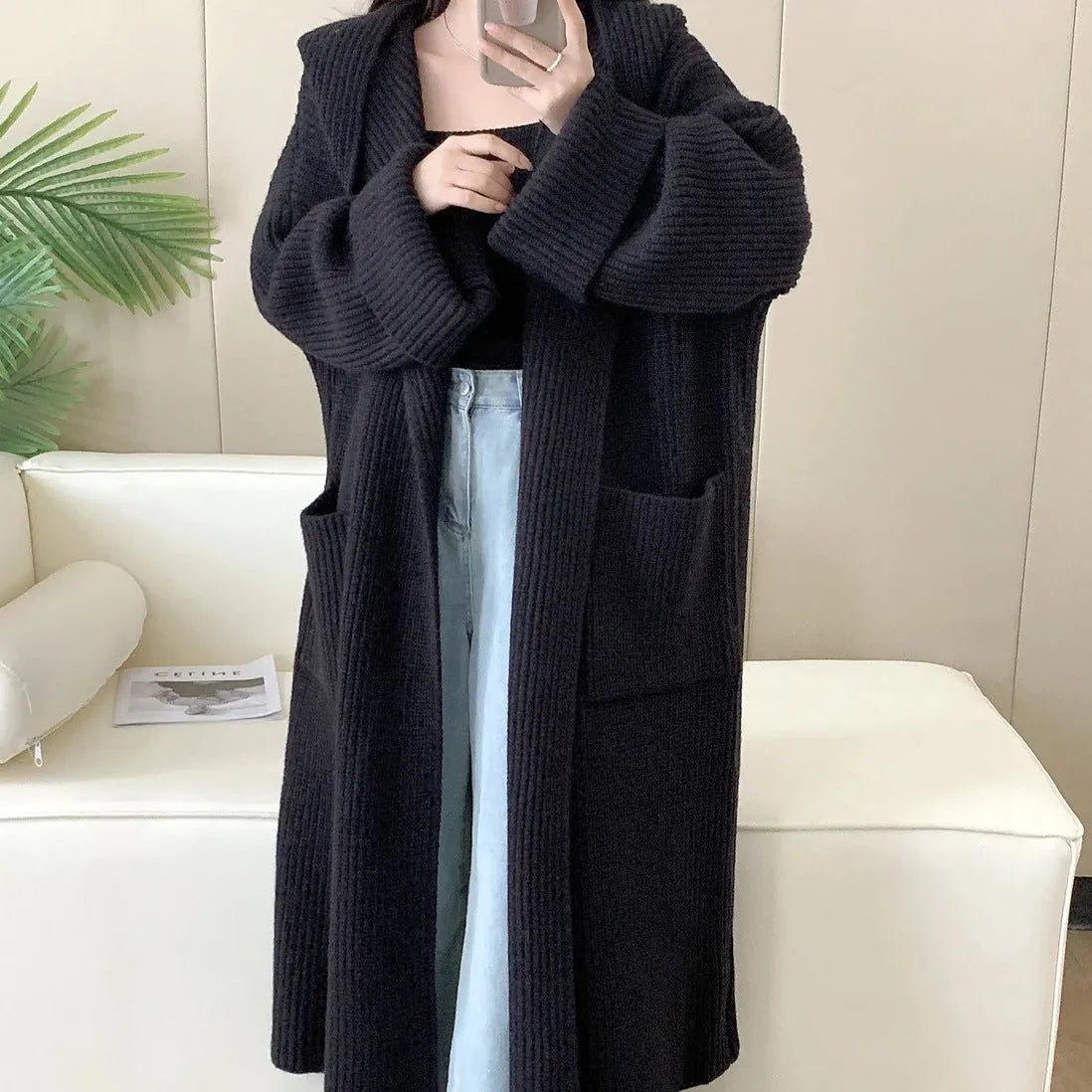 A woman wearing a longline milky white hooded cardigan sweatshirt with raglan sleeves.