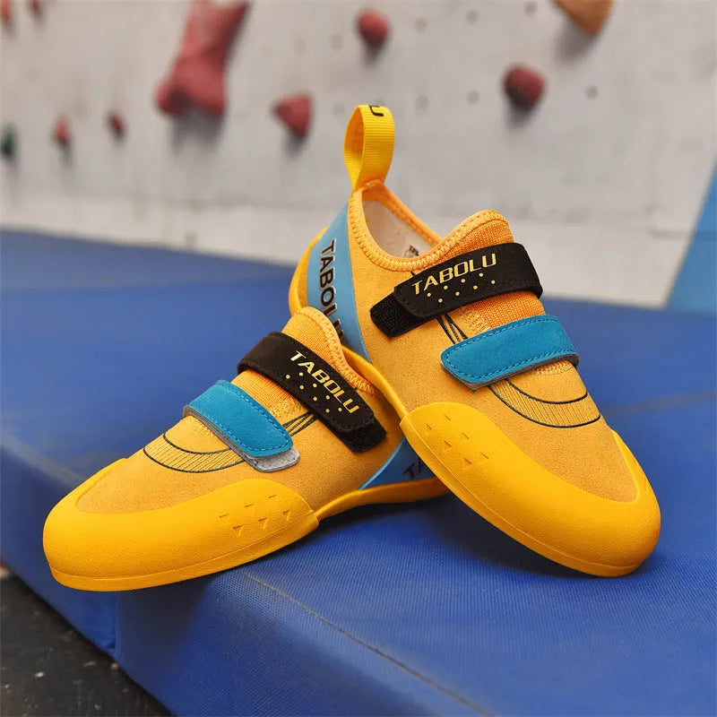 Black beginner rock climbing shoes with Velcro straps and a coloured accent on a rubber sole.