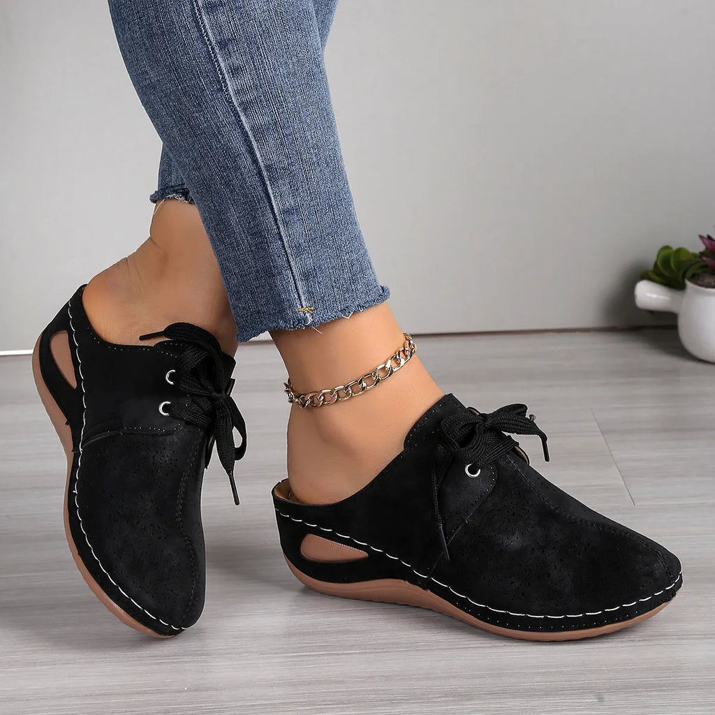 Women's black lace-up wedge slippers with a suede upper and hollow-out rubber sole on a light background.