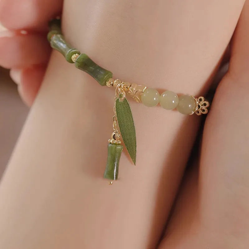 A Chinese style glass bracelet with bamboo leaf and bead designs on a wrist.