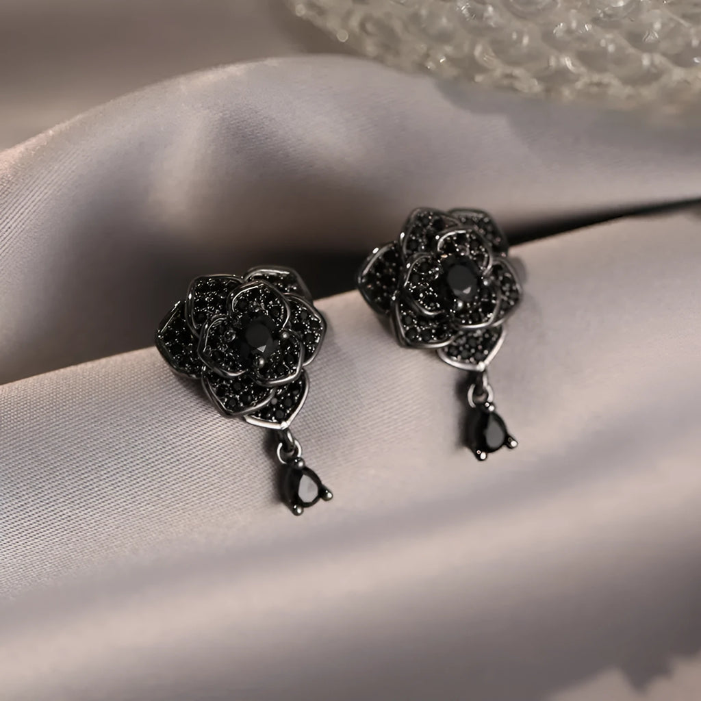 Close-up of women's floral stud earrings with a black rose zircon stone and gold electroplated finish.