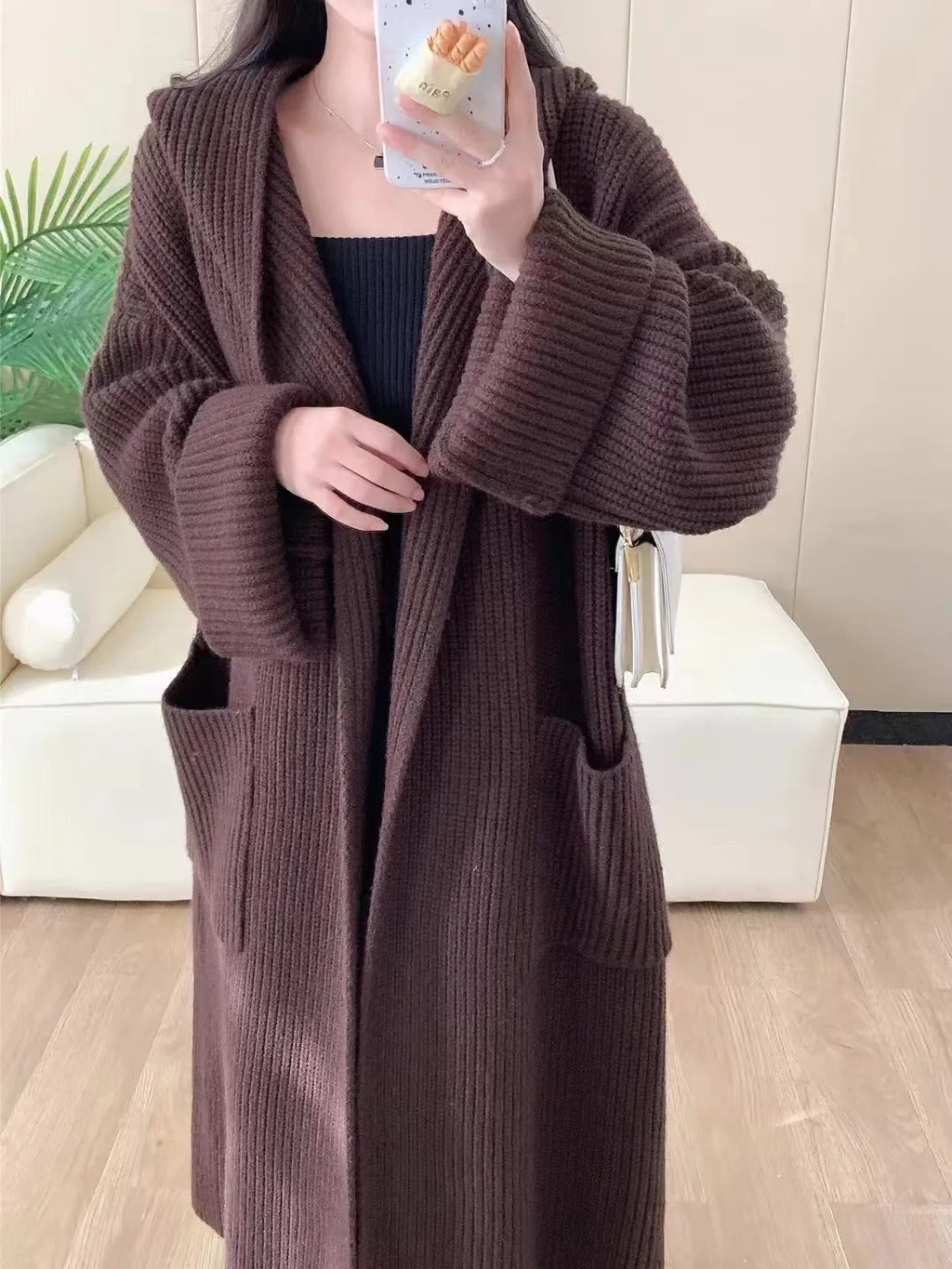 A woman wearing a longline milky white hooded cardigan sweatshirt with raglan sleeves.