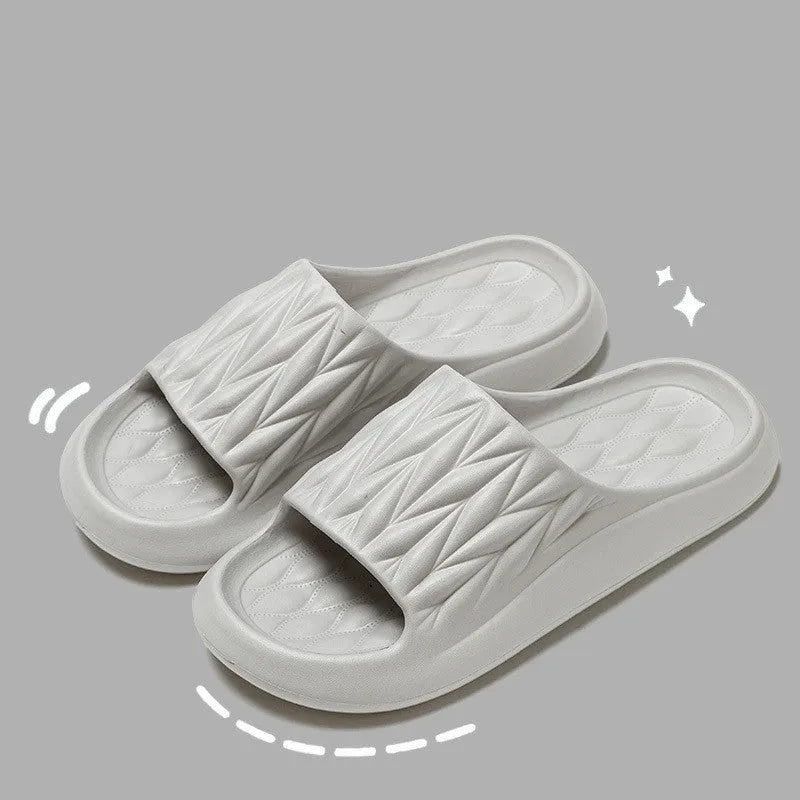 Pair of grey EVA foam slippers with leaf texture pattern and non-slip sole.