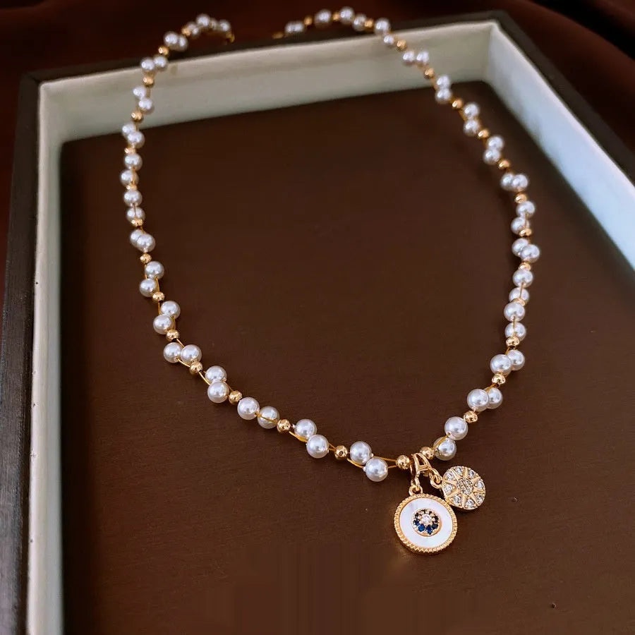 Gold electroplated zircon and imitation pearl round pendant on an adjustable clavicle chain necklace.