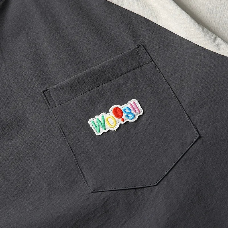 Dark grey loose fit T-shirt with contrast colour raglan sleeves on a hanger.
