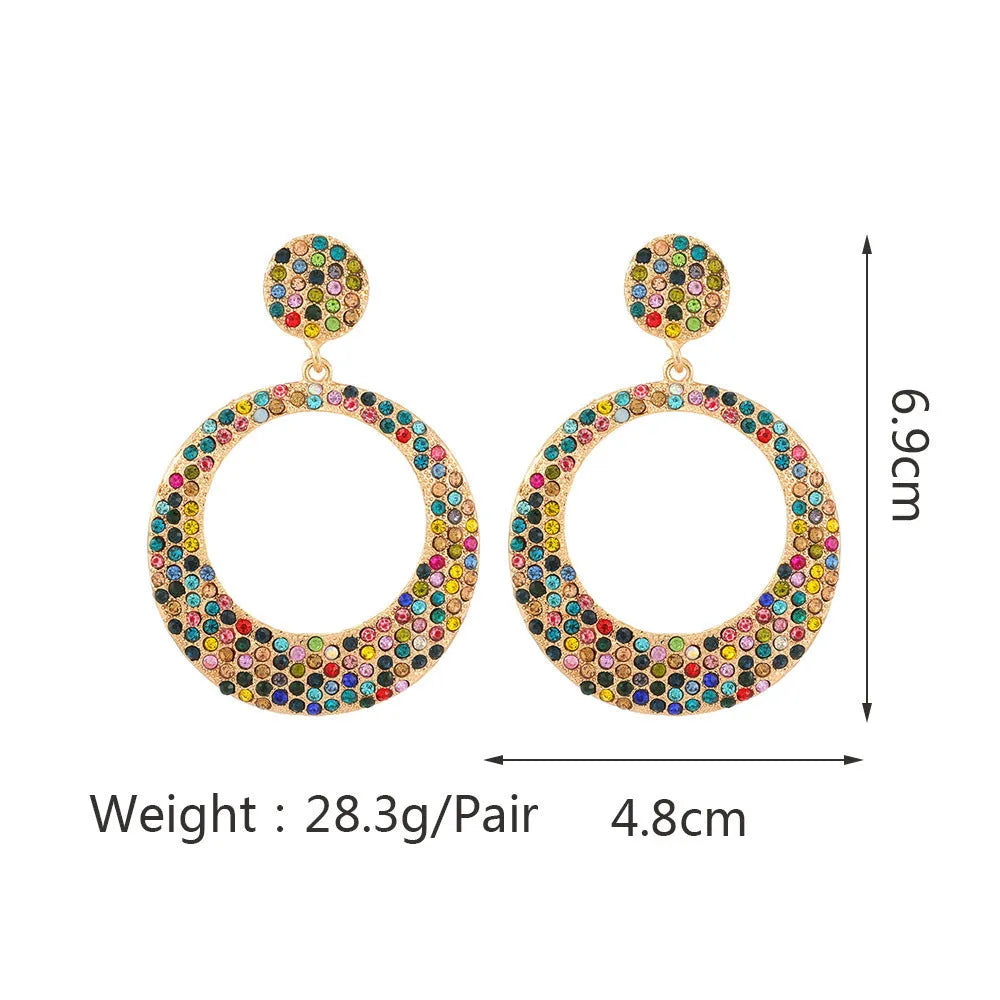 A pair of large round metal pendant earrings with diamond detailing in a cartoon style.
