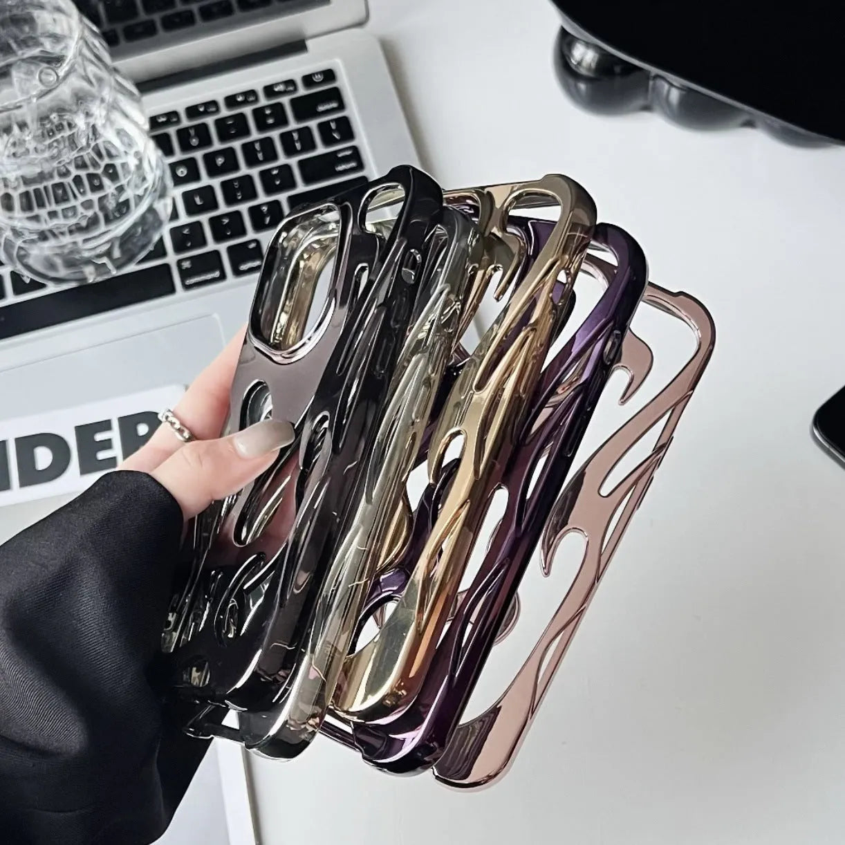 Electroplated iPhone case with hollow flame pattern design in gold, black, purple, and silver finishes