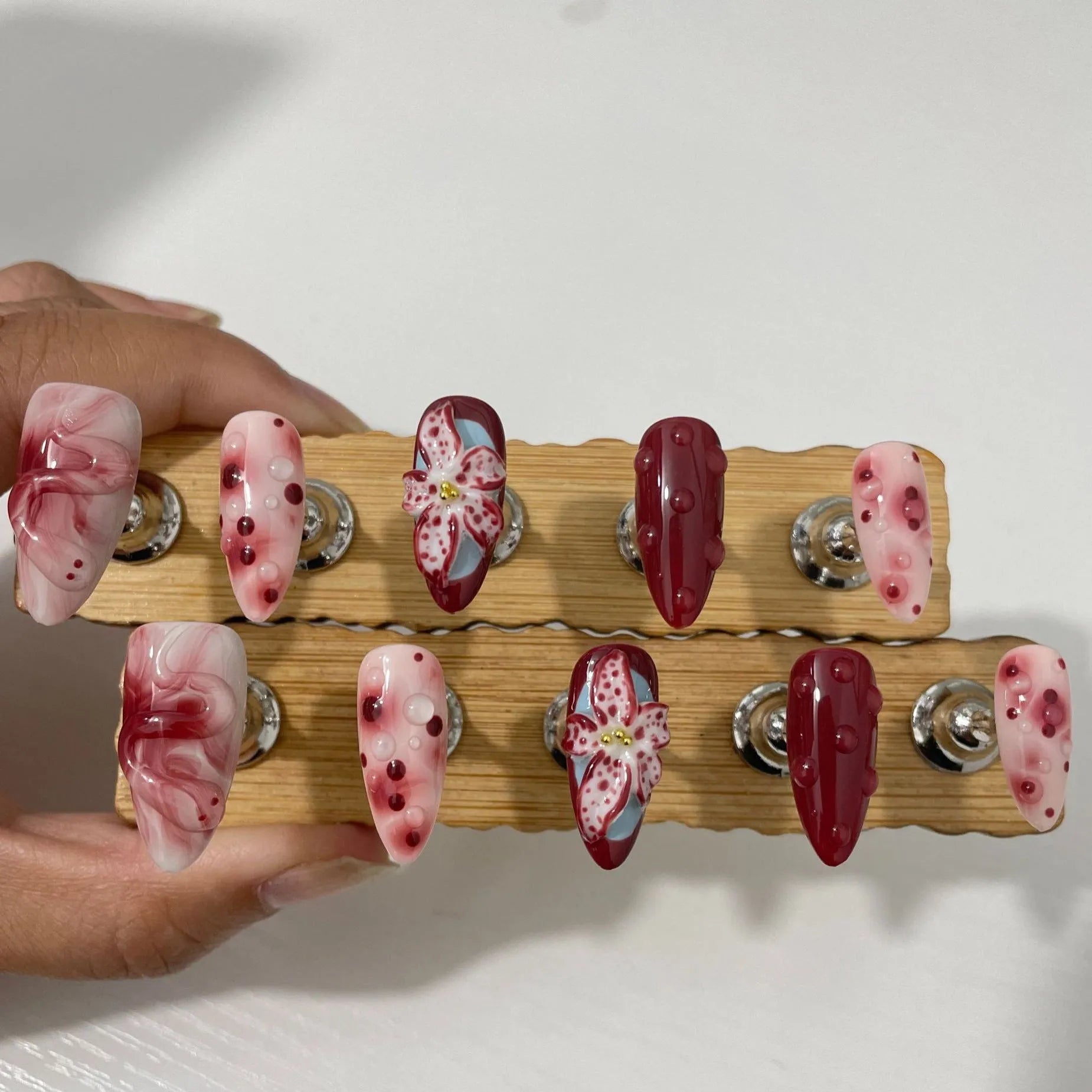 Almond shaped false nails with hand-painted 3D carved rose and tulip designs on a medium length nail.