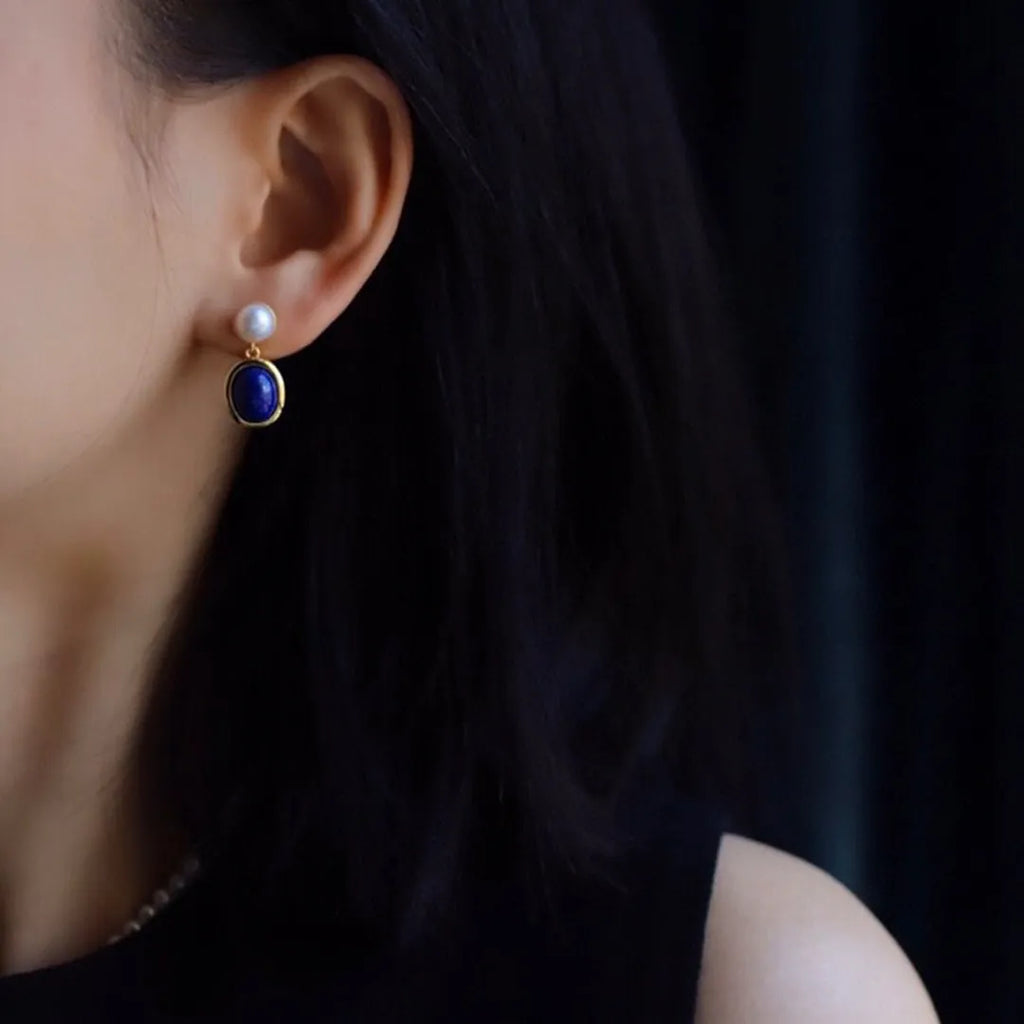 A pair of simple stud earrings featuring a deep blue lapis lazuli pearl set in 925 silver.