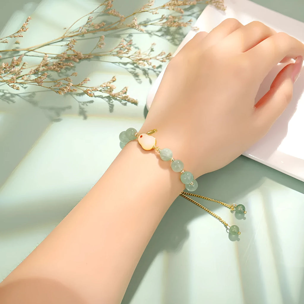 Women's rabbit charm bracelet with green aventurine stones and silver and gold plated metal links.