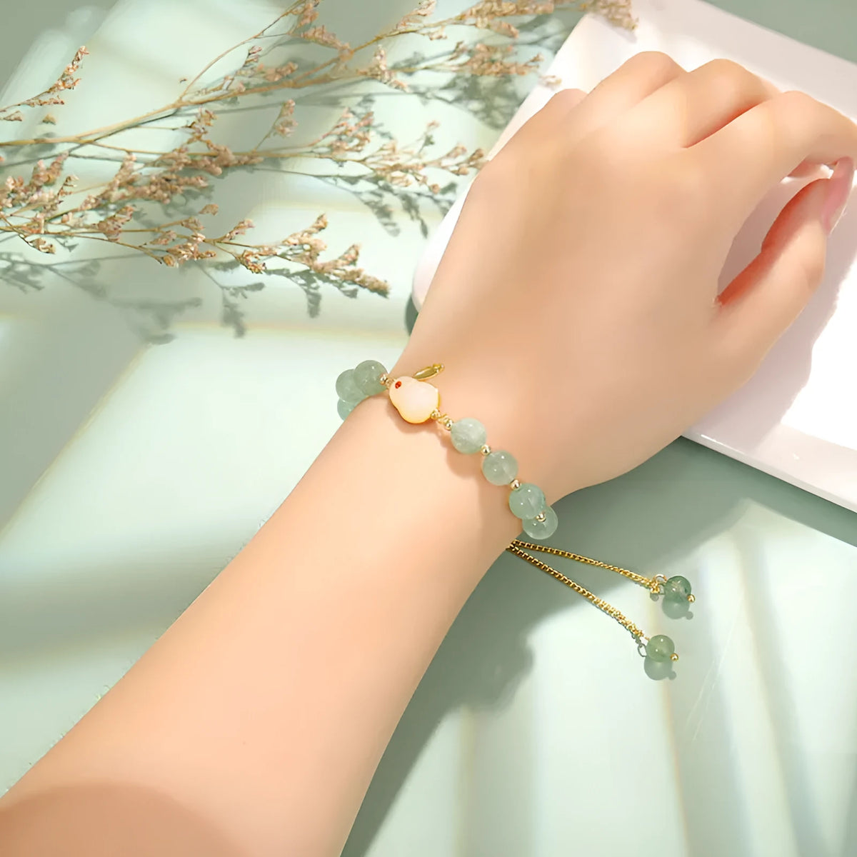 Women's rabbit charm bracelet with green aventurine stones and silver and gold plated metal links.