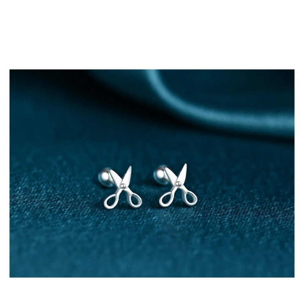 A pair of pure silver screw-back ear nails with a miniature scissors design.