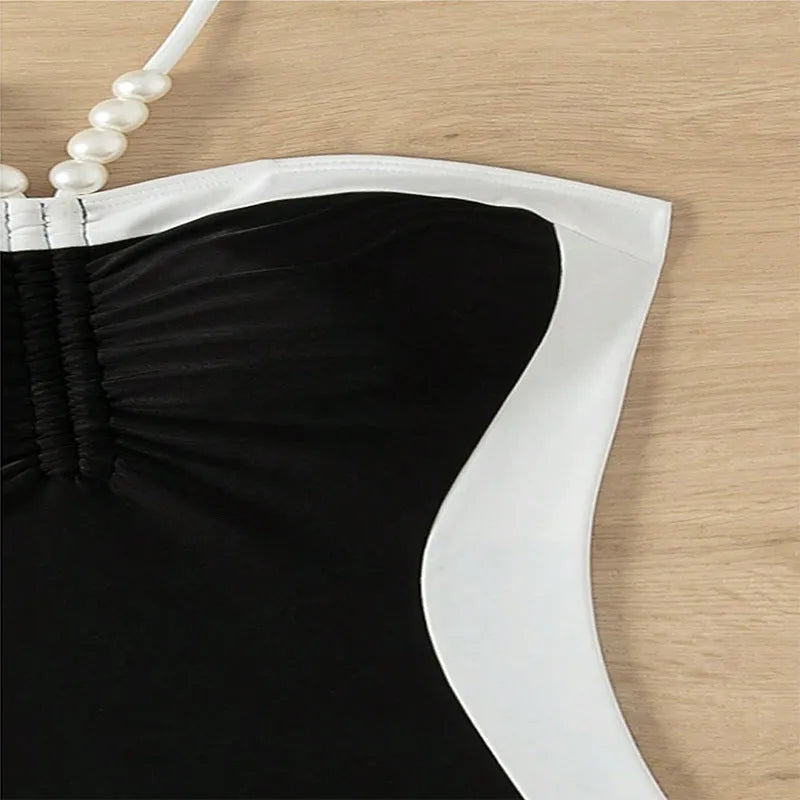 Black and white women's one-piece swimsuit with pearl spaghetti straps and a slimming cut.