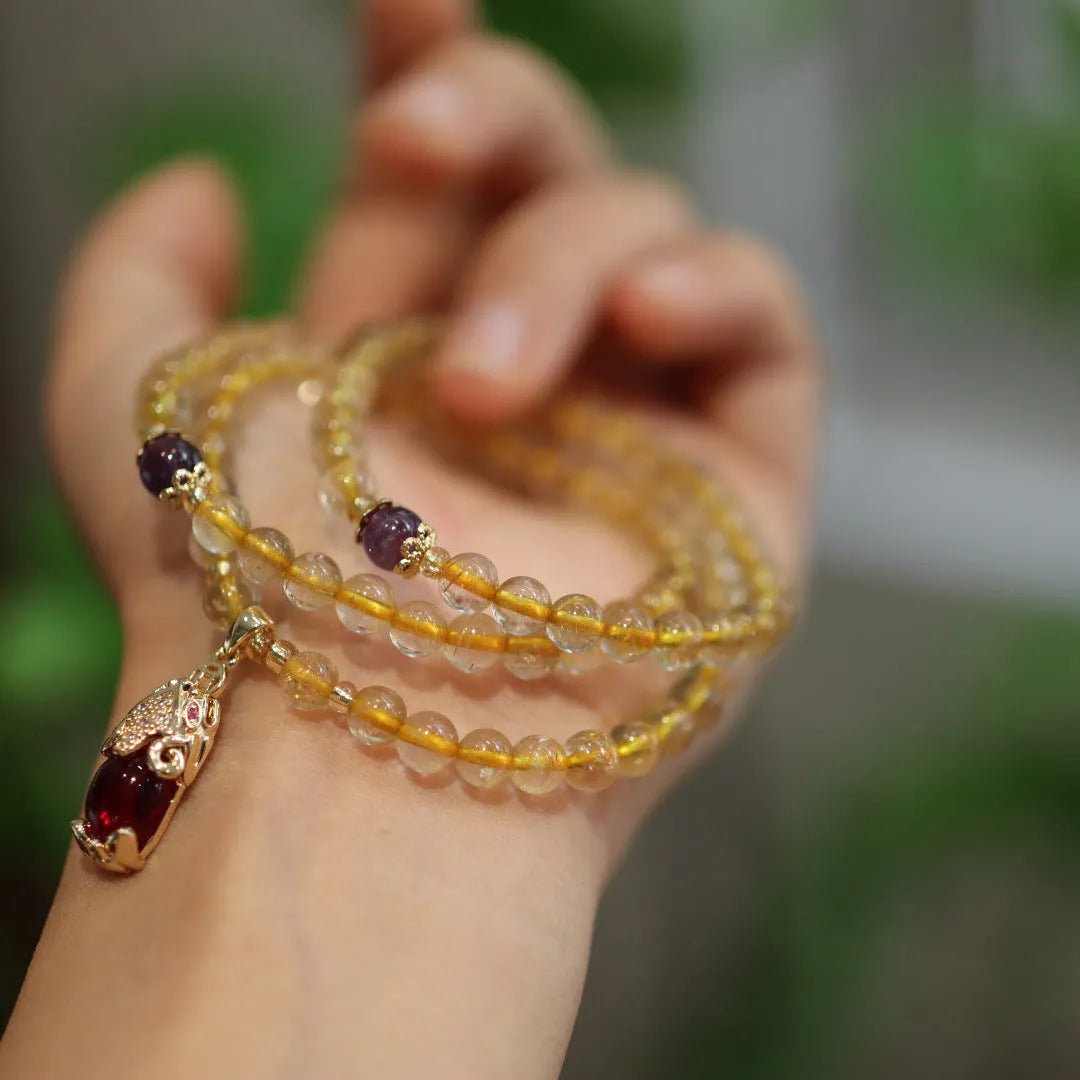 Brazil gold rutilated quartz bracelet with three gold circles in a Chinese style, hanging from chopsticks.