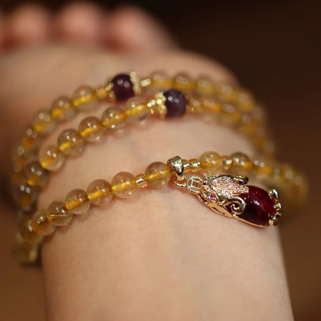 Brazil gold rutilated quartz bracelet with three gold circles in a Chinese style, hanging from chopsticks.