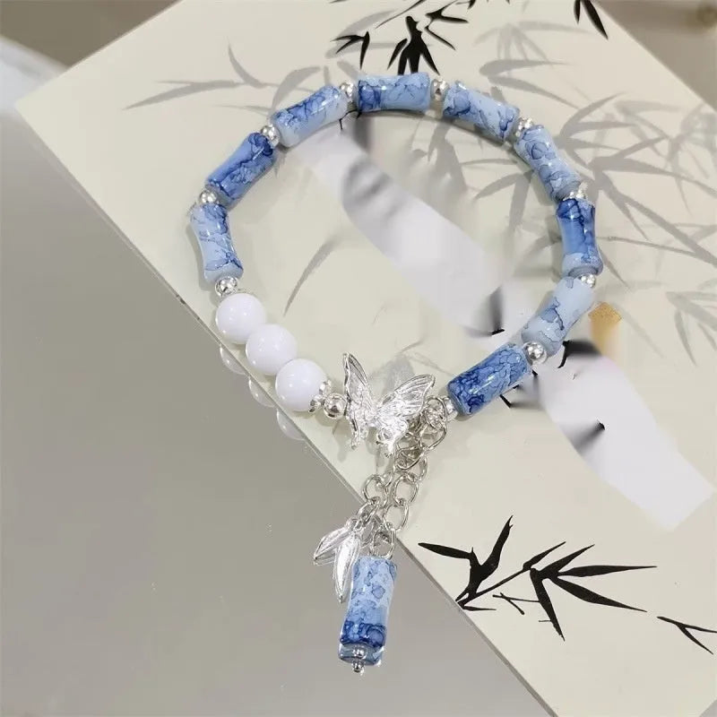 A Chinese style glass bracelet with bamboo leaf and bead designs on a wrist.