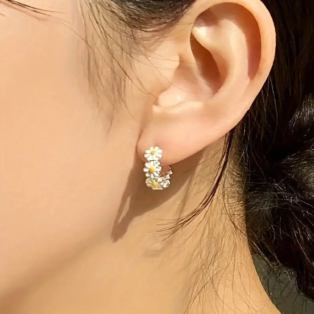 A pair of white daisy flower ring earrings with a platinum-inlaid gemstone detail.