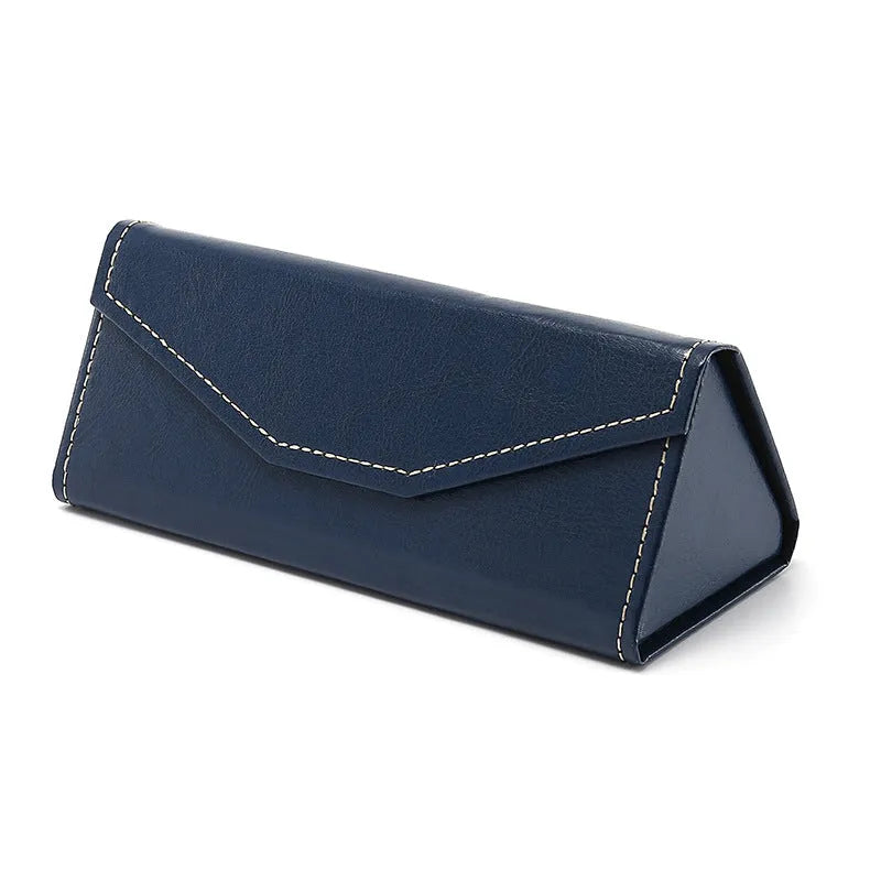 Handmade black PU cowhide triangular folding glasses case open next to a pair of spectacles.