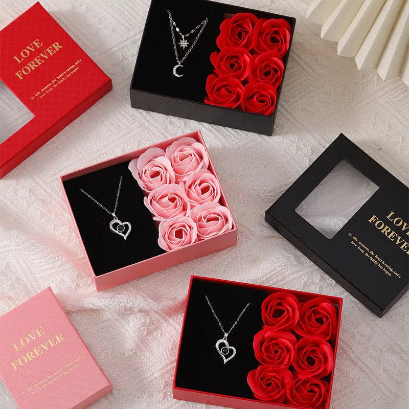 Red, pink, and black soap flower gift sets presented in a box with a handbag-style carrier.