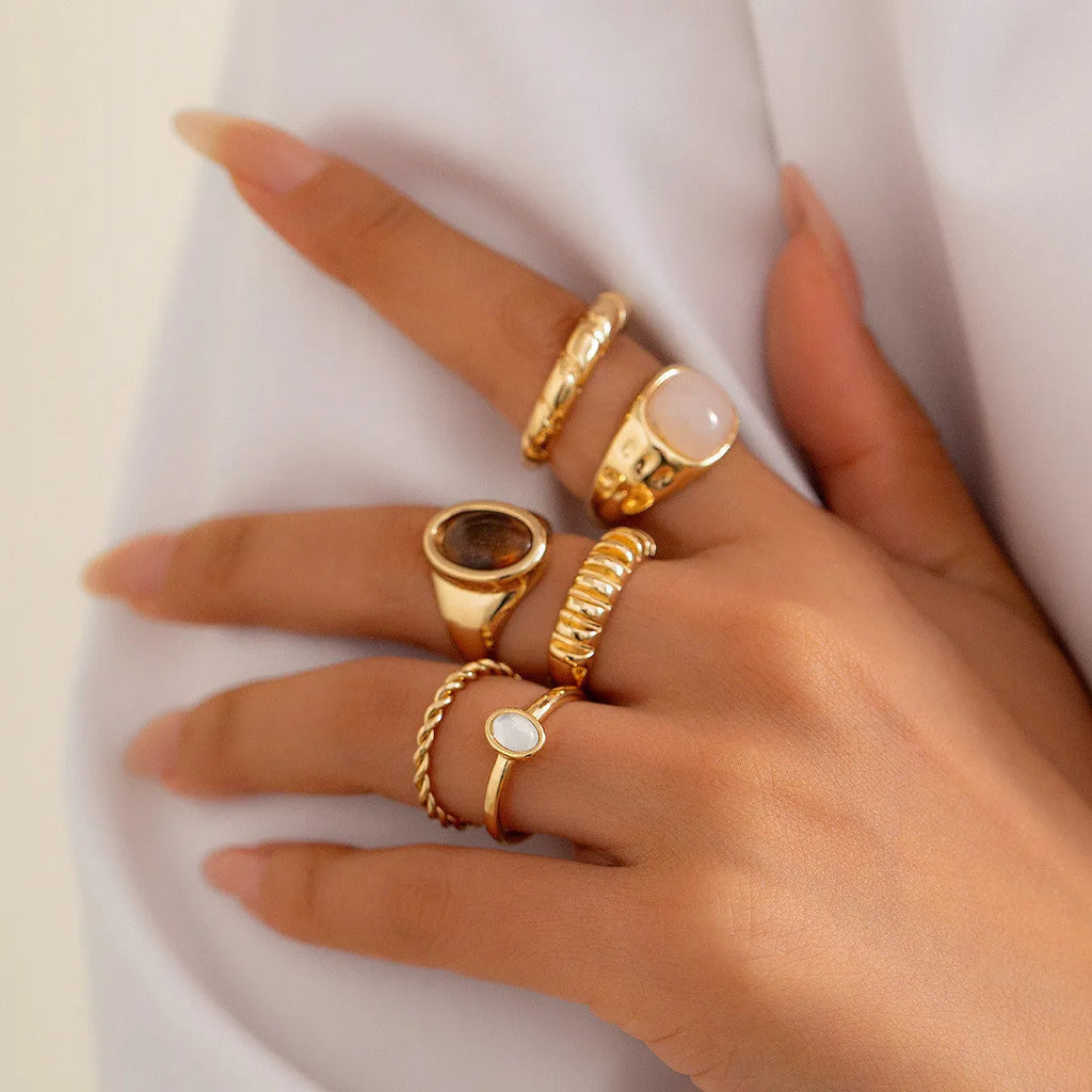 Six light gold geometric alloy rings with irregular shapes and electroplated finish arranged as a complete set