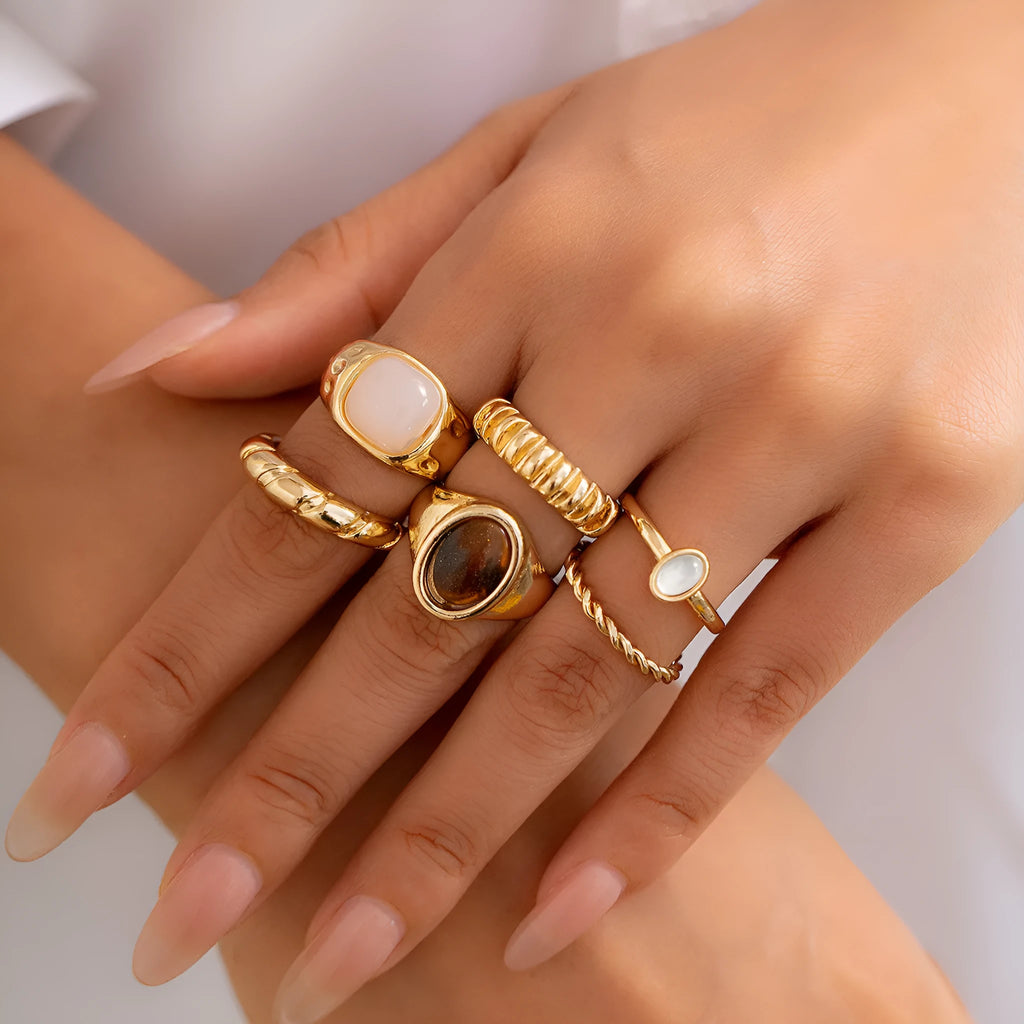 Six light gold geometric alloy rings with irregular shapes and electroplated finish arranged as a complete set