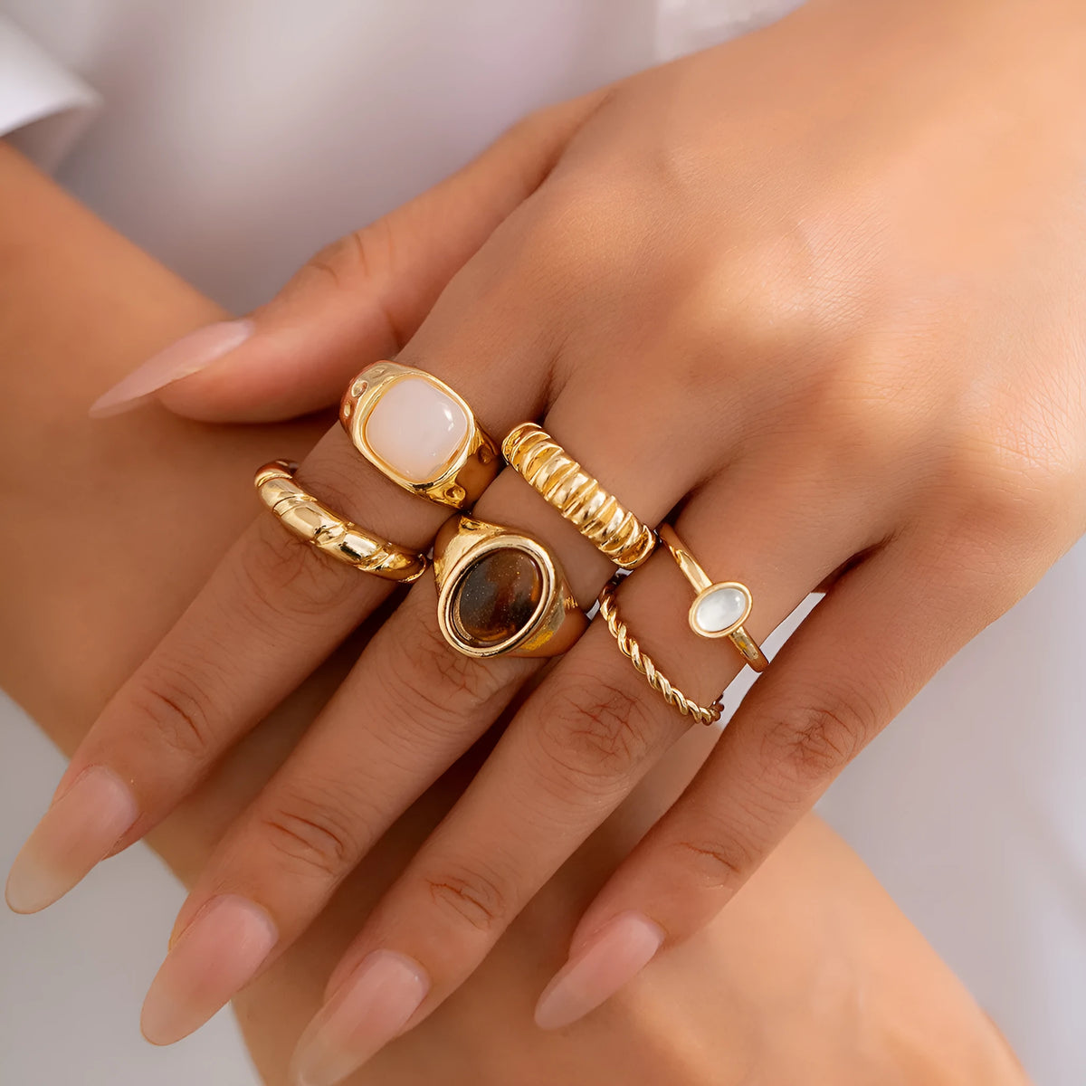 Six light gold geometric alloy rings with irregular shapes and electroplated finish arranged as a complete set