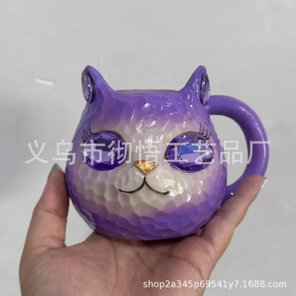 Small resin cat cup figurine in purple, green, blue, or pink colour on a shelf.