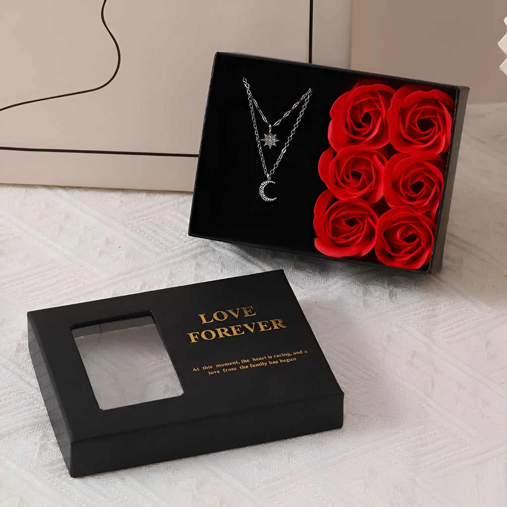 Red, pink, and black soap flower gift sets presented in a box with a handbag-style carrier.