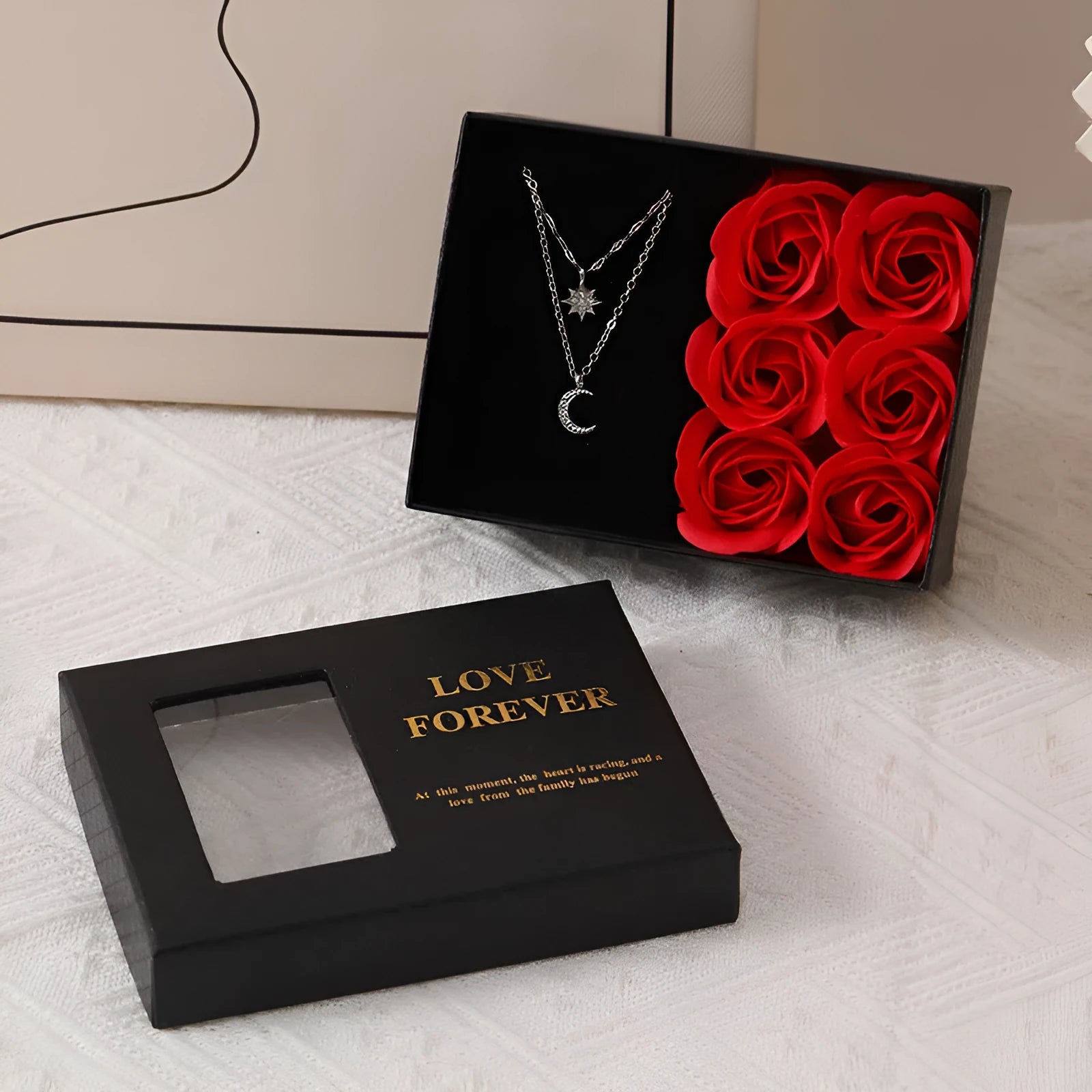 Red, pink, and black soap flower gift sets presented in a box with a handbag-style carrier.