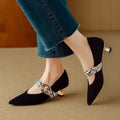 Black women's stiletto high heels with pointed toe and decorative ankle buckle on a rubber sole.