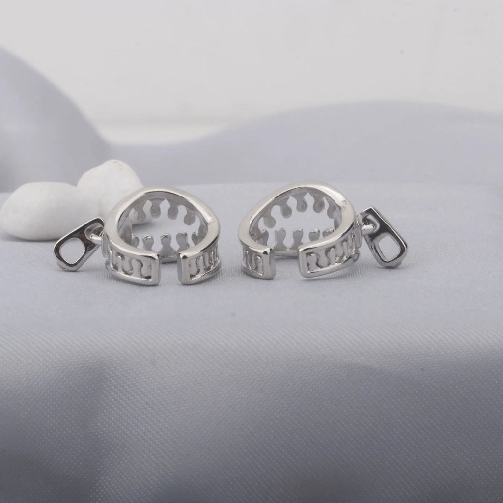 A pair of silver-tone geometric openwork clip-on earrings with a zipper design detail.