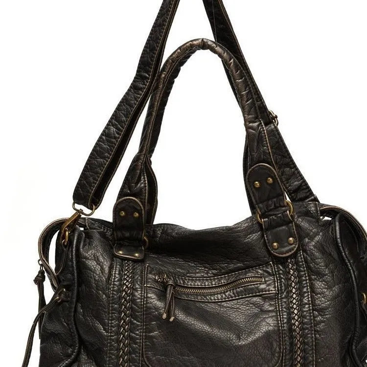 Women's brown soft PU French retro motorcycle shoulder messenger bag with woven design on a table.