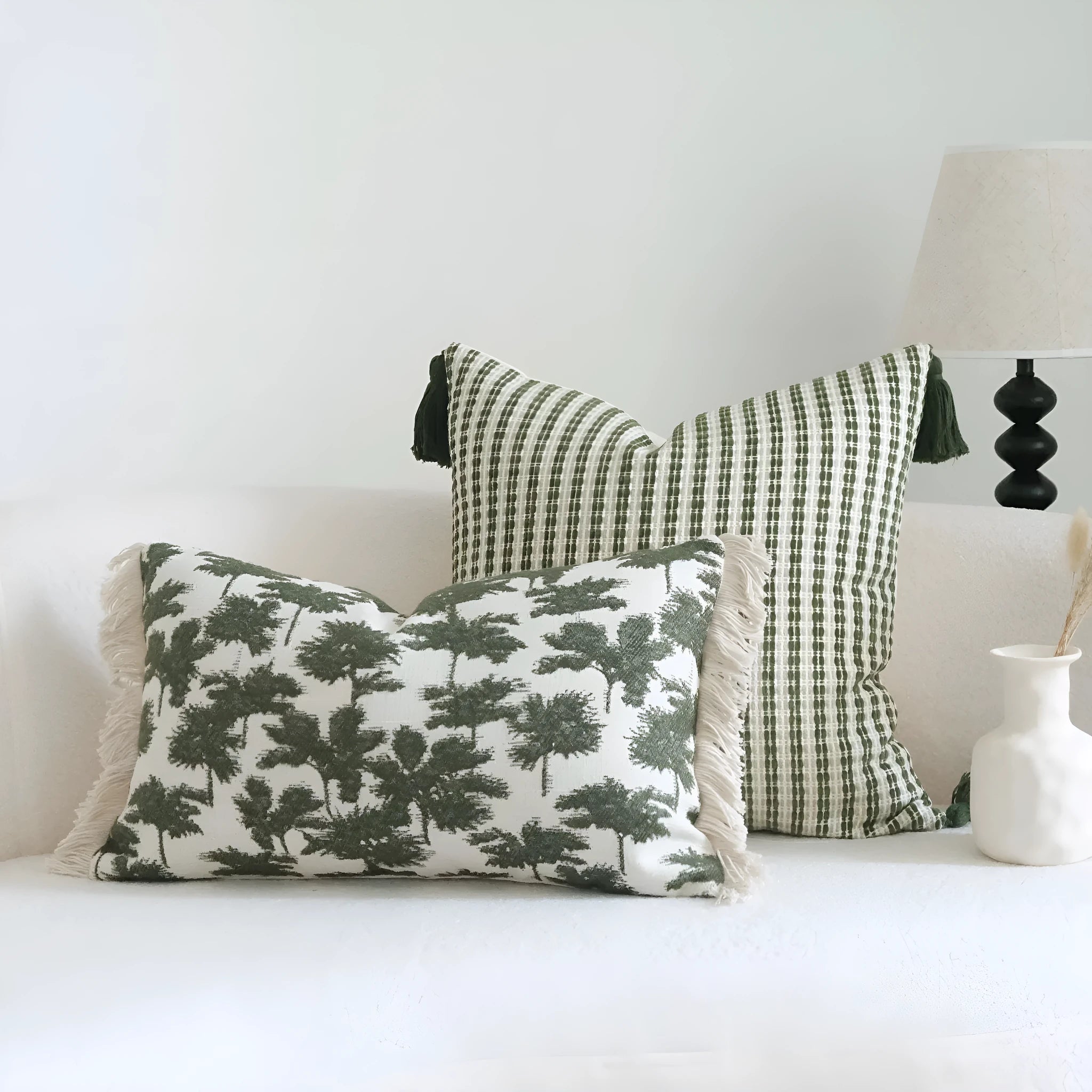 Green striped and botanical pattern decorative pillow set with tassel detail for hotel sample rooms.