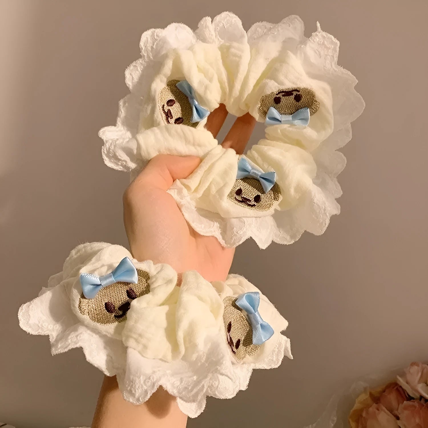 Close-up of a blue cloth hair ring featuring a decorative bear with a blue bow and lace, shown in a large intestine loop design.