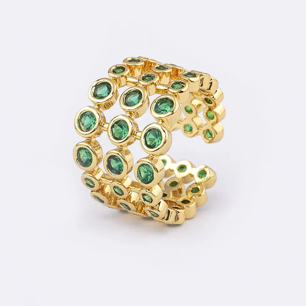 Copper and gold plated wide band ring with green zircon stones on a white background.