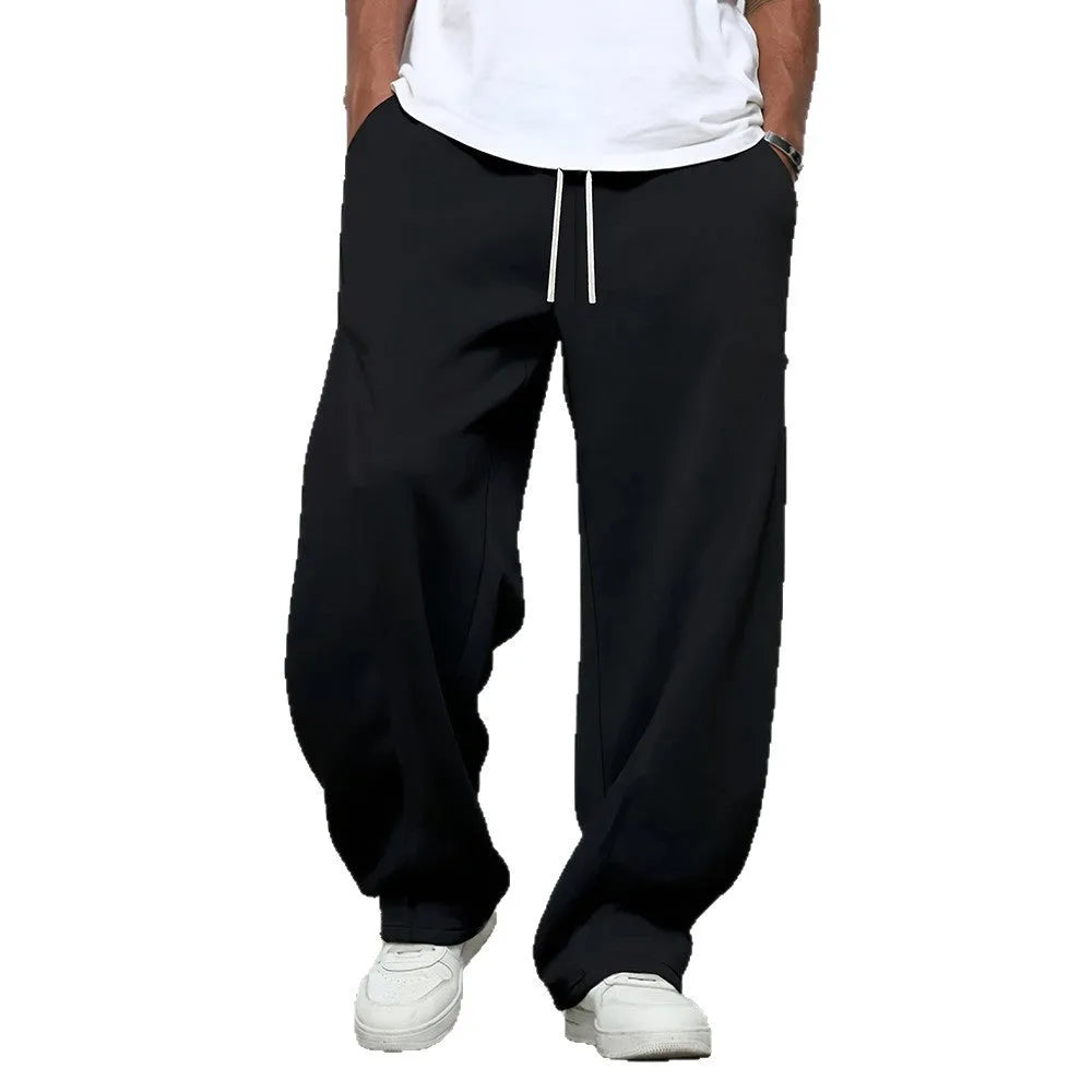 Men's straight-leg casual trousers in black with a drawstring waist, shown flat.