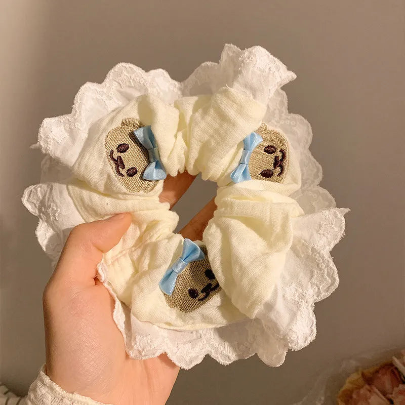 Close-up of a blue cloth hair ring featuring a decorative bear with a blue bow and lace, shown in a large intestine loop design.