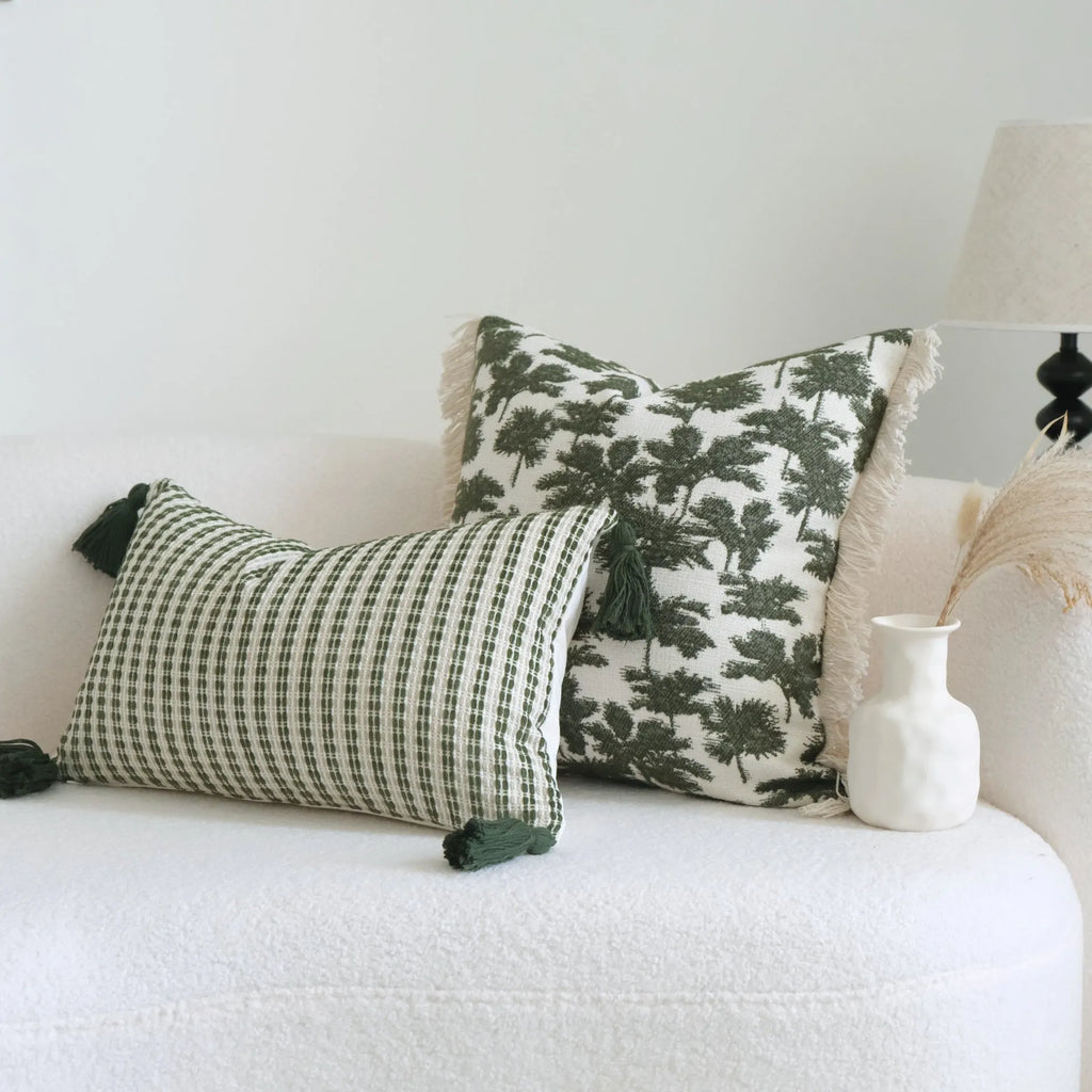 Green striped and botanical pattern decorative pillow set with tassel detail for hotel sample rooms.