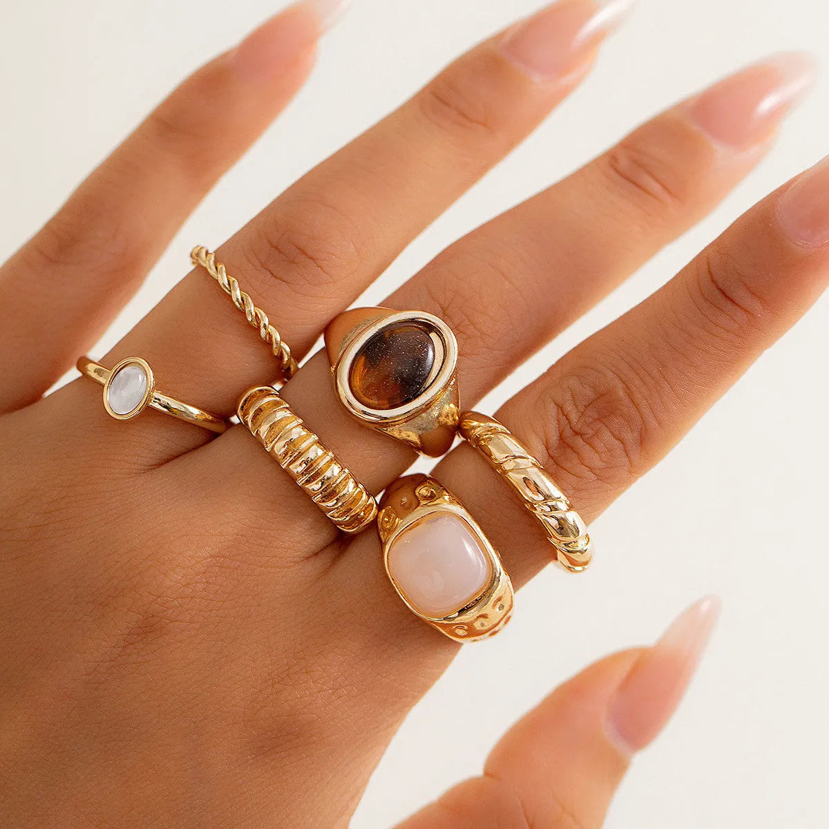 Six light gold geometric alloy rings with irregular shapes and electroplated finish arranged as a complete set