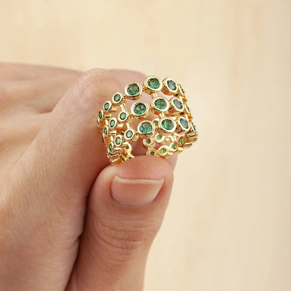 Copper and gold plated wide band ring with green zircon stones on a white background.