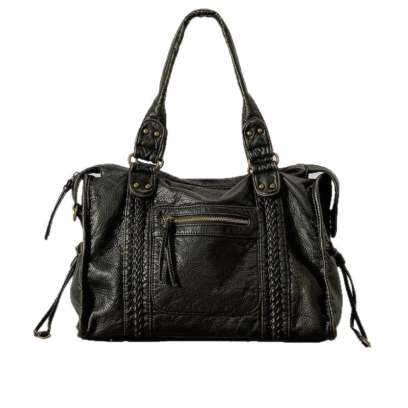 Women's brown soft PU French retro motorcycle shoulder messenger bag with woven design on a table.