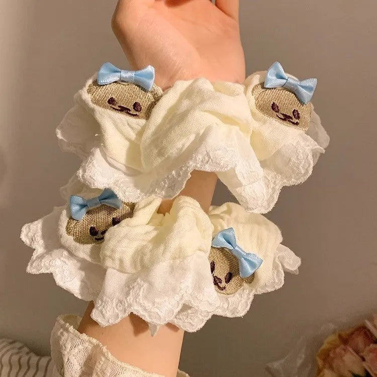 Close-up of a blue cloth hair ring featuring a decorative bear with a blue bow and lace, shown in a large intestine loop design.