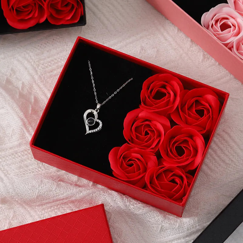 Red, pink, and black soap flower gift sets presented in a box with a handbag-style carrier.