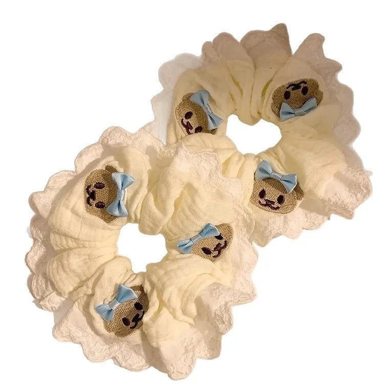 Close-up of a blue cloth hair ring featuring a decorative bear with a blue bow and lace, shown in a large intestine loop design.
