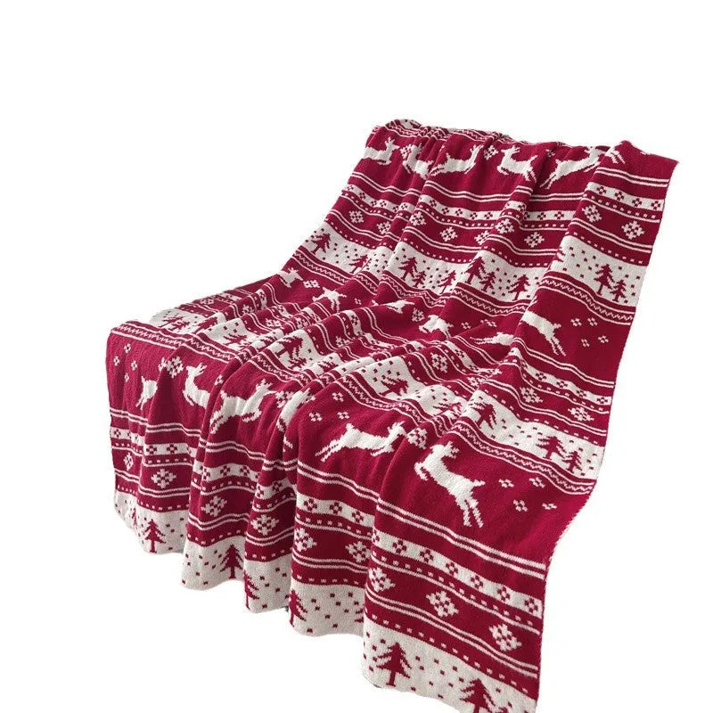 Personalised Christmas blanket with snowflake or reindeer design on a sofa.